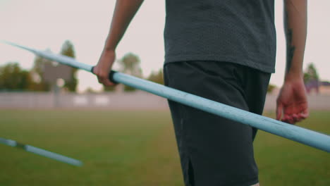 Close-up:-Hand-a-Male-athlete-at-the-stadium-takes-a-javelin-for-throwing-and-prepares-to-make-a-throw.-Goes-takes-the-spear.-Training-of-a-javelin-thrower